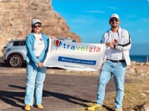 Travellers holding a Travelzia banner at Cape of Good Hope, South Africa